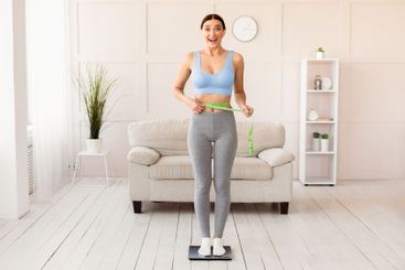 Woman Measuring Waist Standing On Scales Losing Weight...