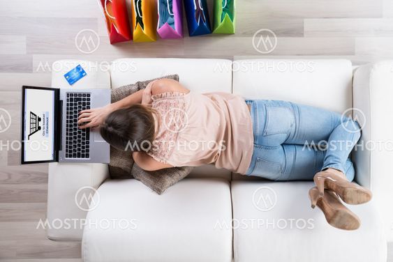Woman On Sofa Shopping Online With Laptop