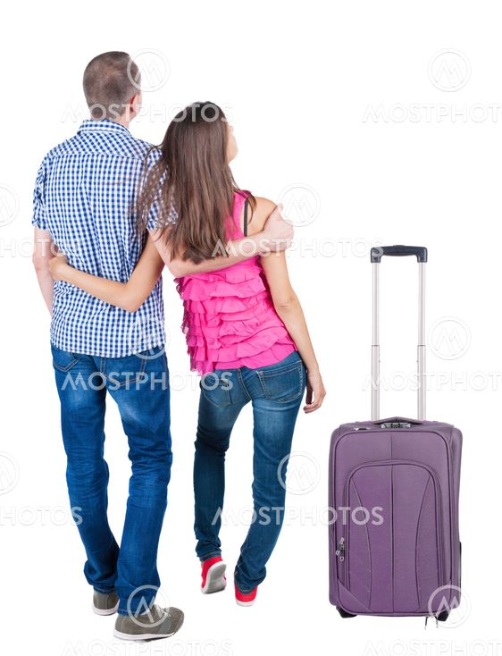 Back view of young couple traveling with suitcas .