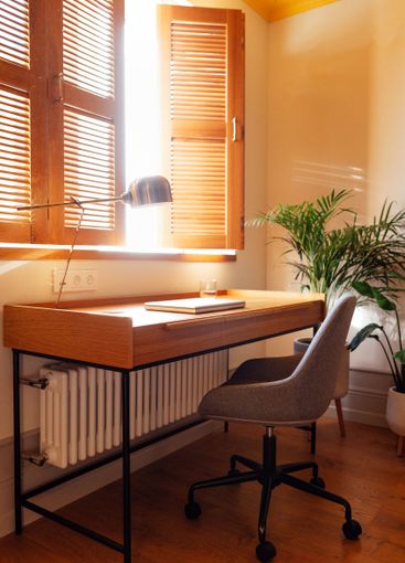 A close-up of a home workplace with a wooden table, a...