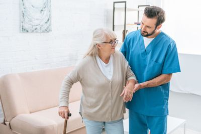 male nurse supporting senior woman in eyeglasses with...
