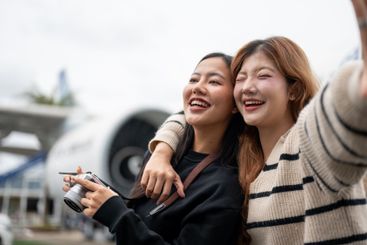 Two female friends, excited for their trip together, are...