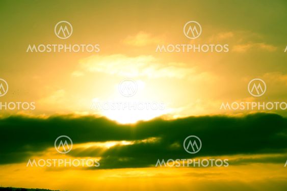 Beautiful sunset behind dark fluffy clouds