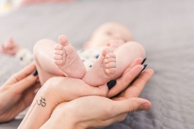 partial view of mother and father holding babys feet...
