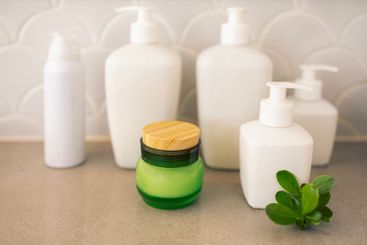 A close-up of a jar of green glass cream with a wooden...