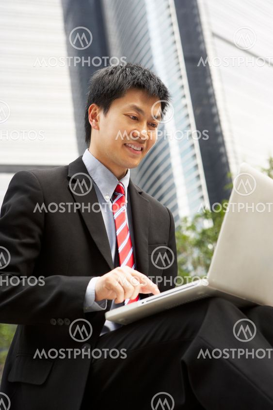 Chinese Businessman Working On Laptop Outside Office