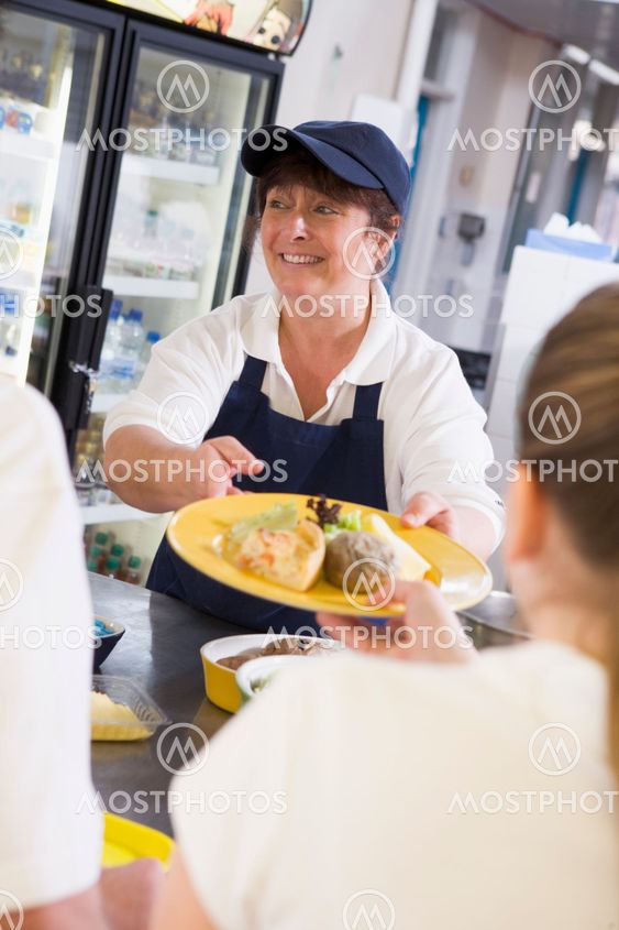 A woman serving lunch to high school students