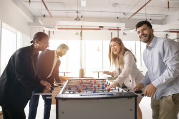Four multiethnic colleagues playing together table football