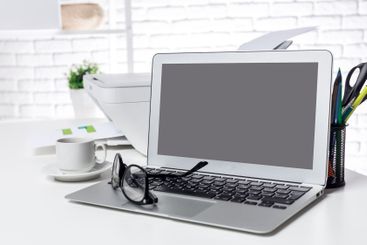 Modern workspace setup with laptop, printer, and coffee...