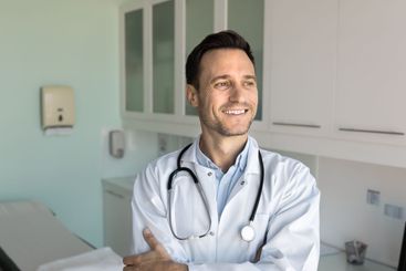 Positive thoughtful handsome male doctor posing in...