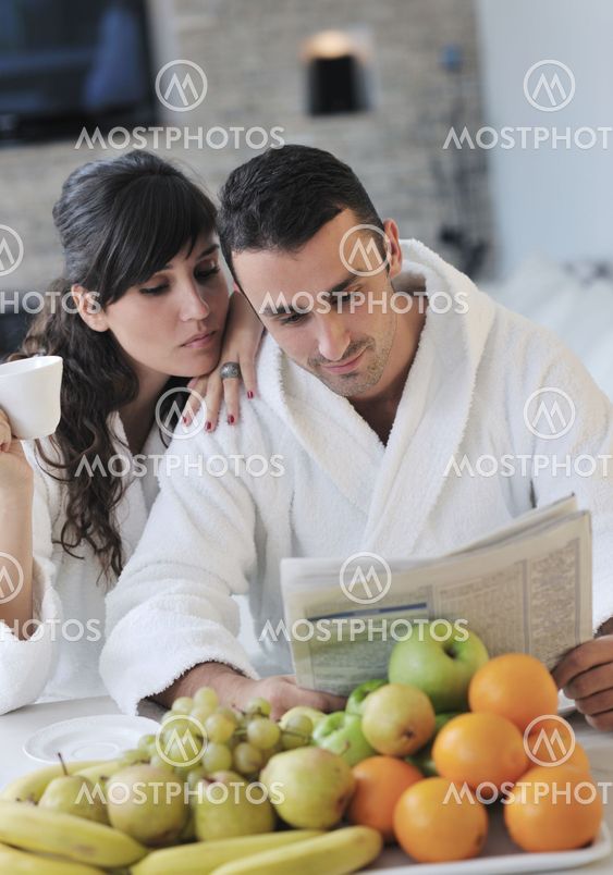Happy couple reading the newspaper in the kitchen at breakfast