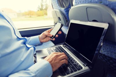 man with smartphone and laptop in travel bus