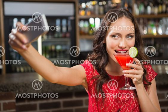 Pretty woman taking a selfie with her cocktail
