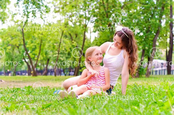 mother and daughter sitting together on the grass
