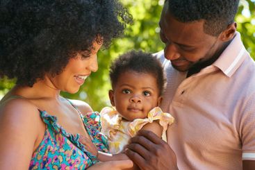 Close Up Of Loving Parents Cuddling Baby Daughter...