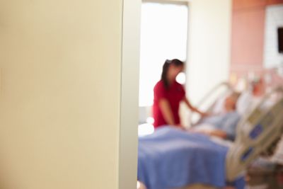 Focus On Hospital Room Sign With Nurse Talking To Patient