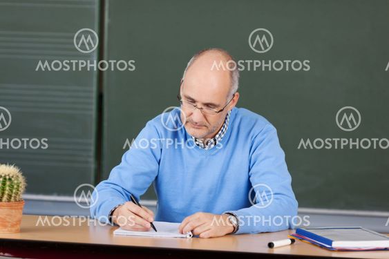 Teacher writing notes at his desk