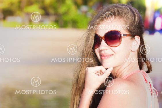 young woman in sunglasses tanning on beach. portrait