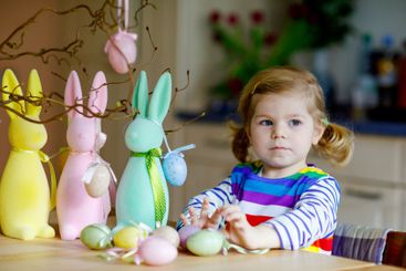 Cute little toddler girl decorating tree and bunny with...