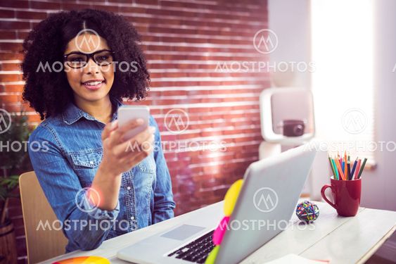 Casual businesswoman using her smartphone and smiling at...