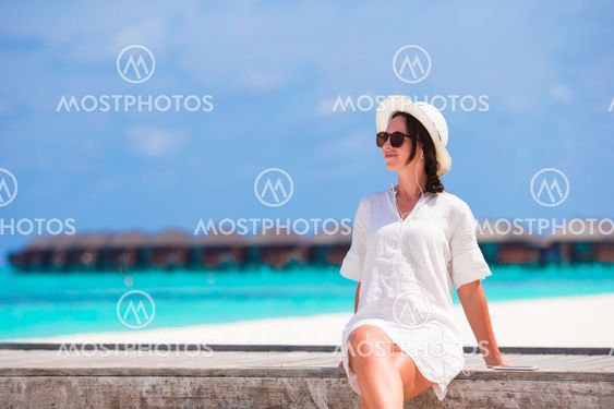 Young beautiful woman listening to music on wooden bridge
