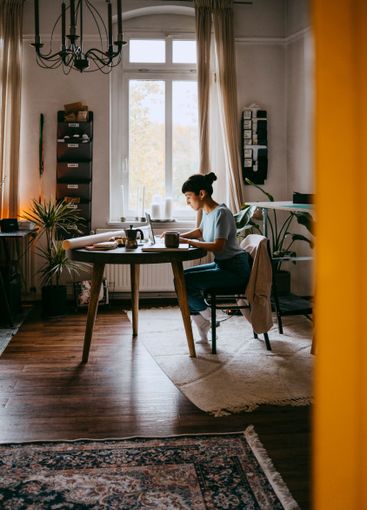 Young female freelancer working on laptop while sitting...