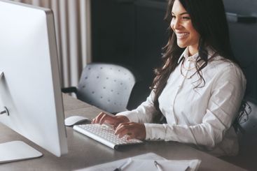 Happy, business woman and typing with computer at office...
