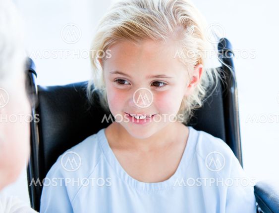 Blond little girl sitting on a wheelchair