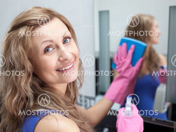 Charming woman cleaning a bathroom's mirror