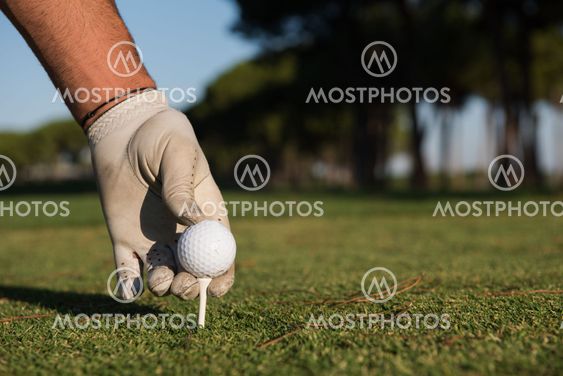 close up of golf players hand placing ball on tee