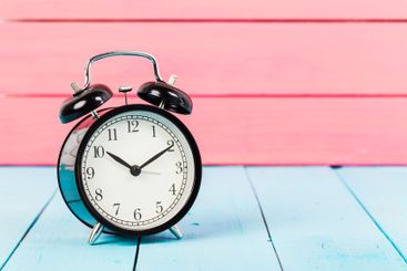 Black vintage alarm clock on wooden table