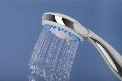 Water pours out of the shower, on a blue background.