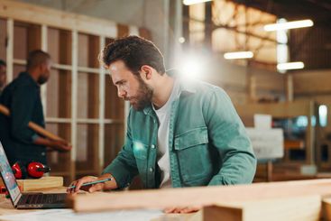 Carpenter, laptop and research with wood to measure for...