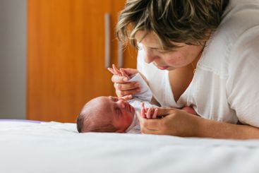 Mother holding hands of her one month old baby son lying...