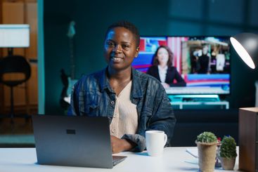 Portrait of happy woman sitting at home office desk in...