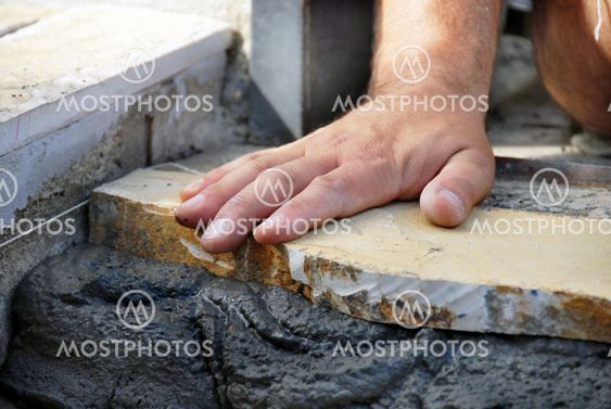 Worker hand on flagstone