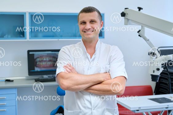 Portrait of confident friendly male dentist with crossed...