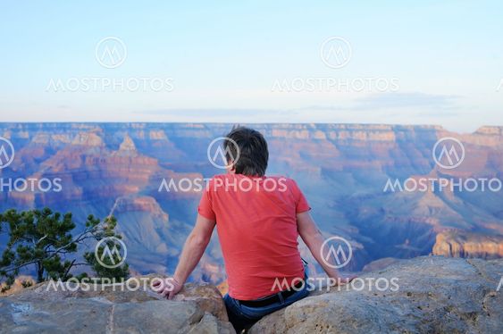 Man sitting on stone and looking of the Grand Canyon