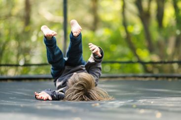 Little boy jumping on a trampoline in a backyard on warm...