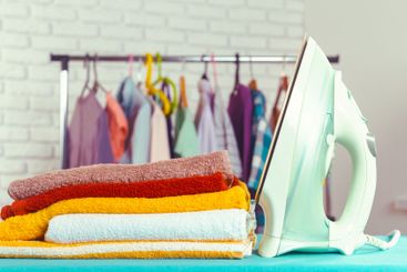 Iron on ironing board on light home interior background