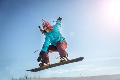 Young woman on the snowboard jumping