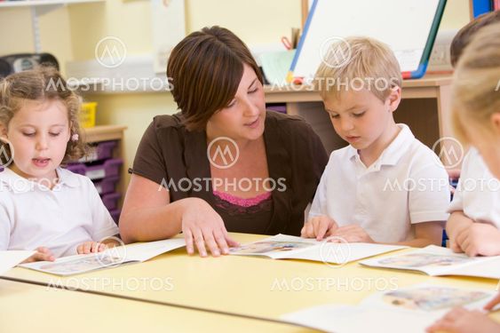 Schoolchildren and their teacher reading in a primary class