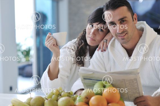 Happy couple reading the newspaper in the kitchen at breakfast