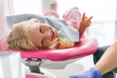 portrait of child showing peace sign at dentist office