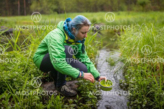 the girl washes tourist dishes by the river at the campsite