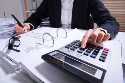 Midsection Of Businessperson Calculating Invoice