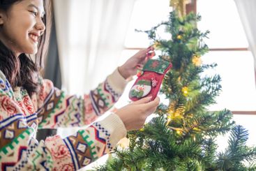 Happy asian woman Decorating Christmas tree for xmas...
