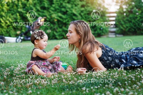 young mother and her little daughter playing on grass