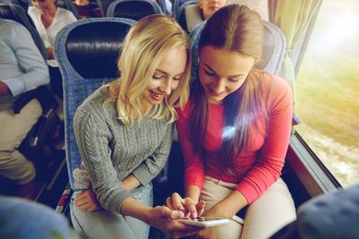 happy young women in travel bus with smartphone