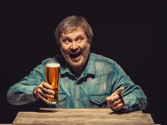 The screaming man in denim shirt with glass of beer
